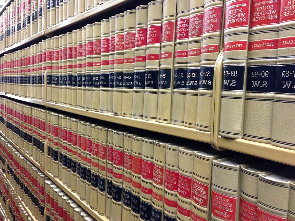 Stack of reference books and digital tablets on a wooden desk
